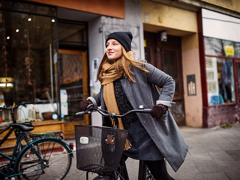 Radlerin in der Stadt mit Mütze und Mantel Radlerin in der Stadt mit Mütze und Mantel